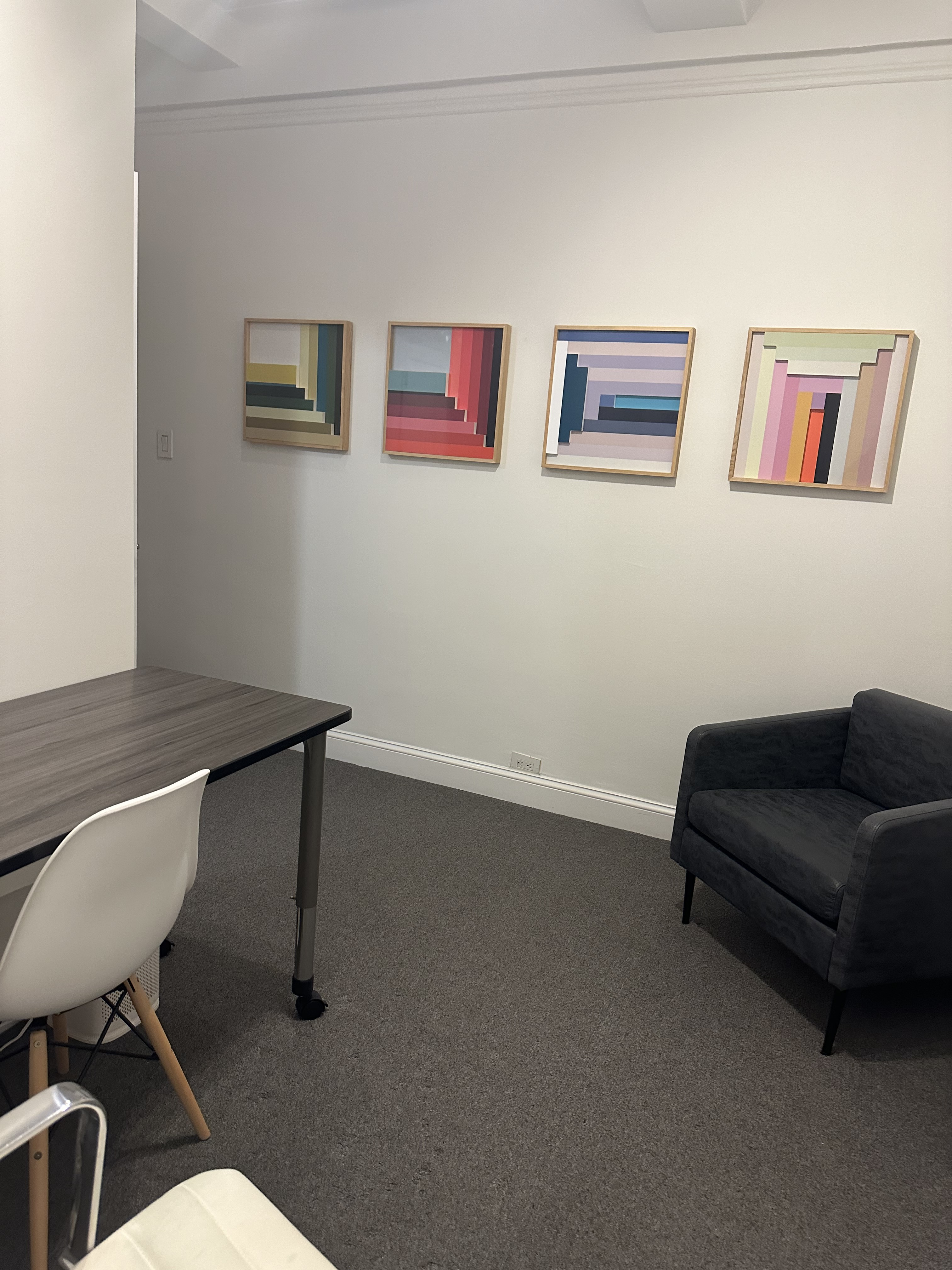 Office interior featuring couch, desk, and art on walls